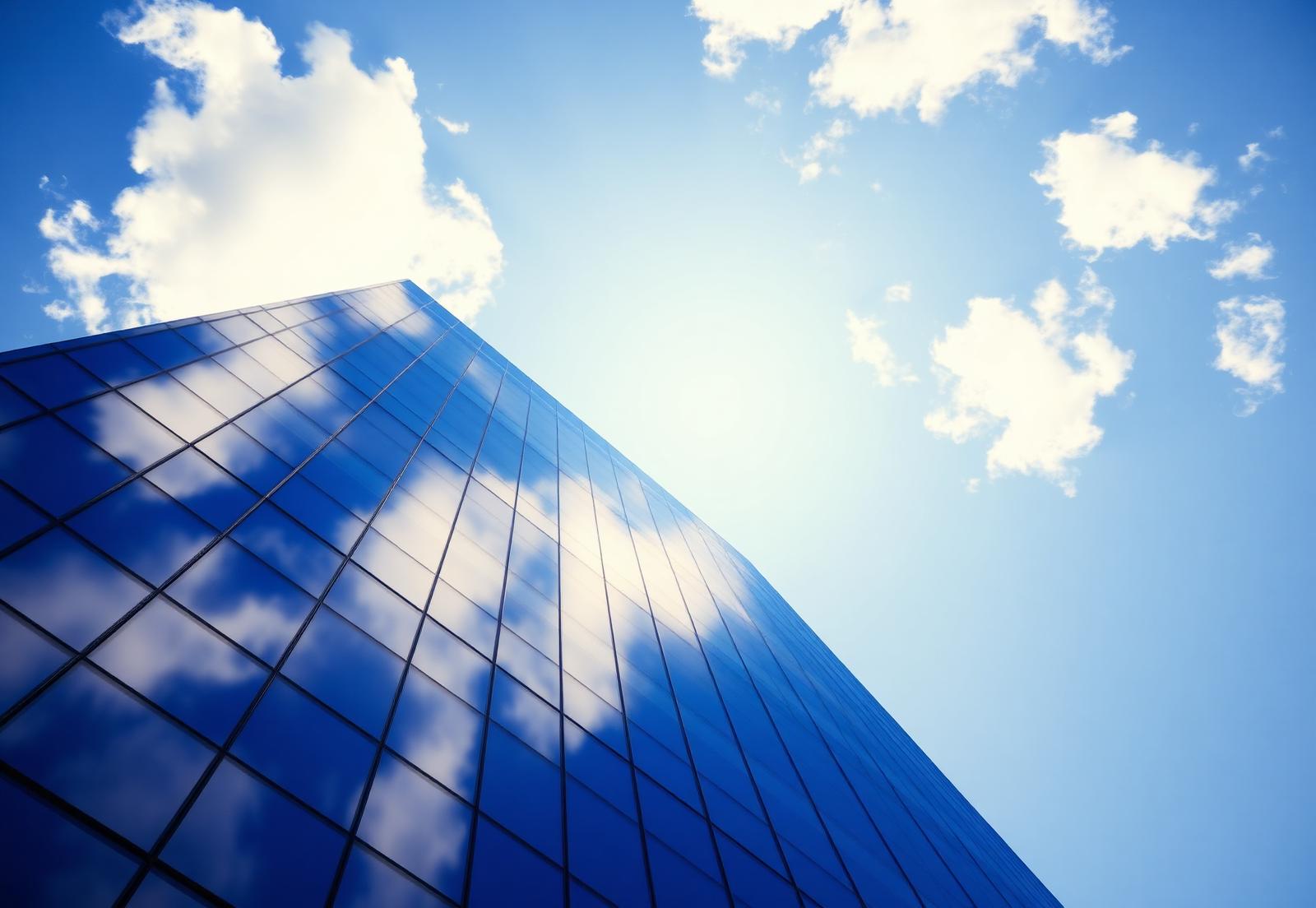 Fachada envidraçada de edifício comercial refletindo o céu